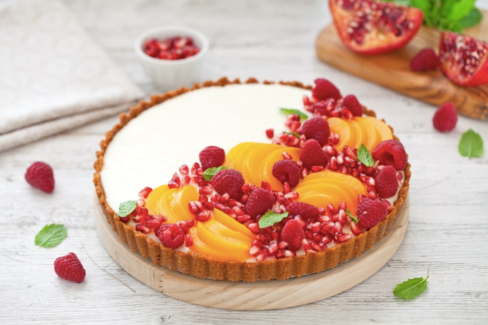 Torta con panna cotta allo yogurt, pesche sciroppate e frutti rossi  ricetta